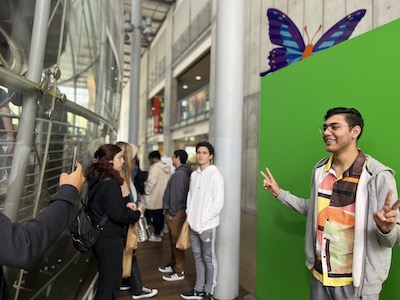 Student posing for a photo in front of a green screen